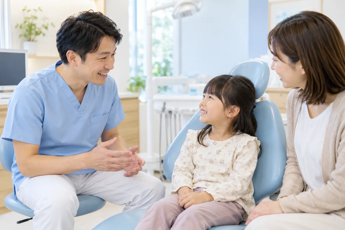 歯科医師が親子と目線を合わせて話す、こどもの歯の相談イメージ(AI生成)